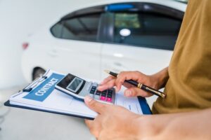 Man completing a car insurance form after an accident, preparing to file a claim and discuss coverage details with an adjuster.